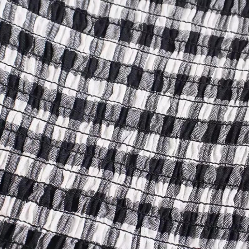 Close-up detail of the Pixi Dress showing black and white gingham fabric with shirred bodice