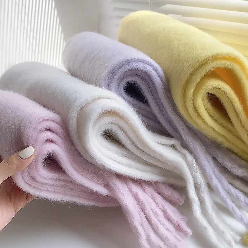 woman holds folded scarves to show the thickness and soft texture of the scarves
