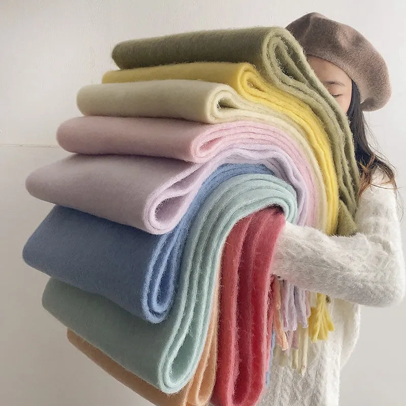 woman holds folded scarves to show the thickness, vibrant colors, and soft texture of the scarves