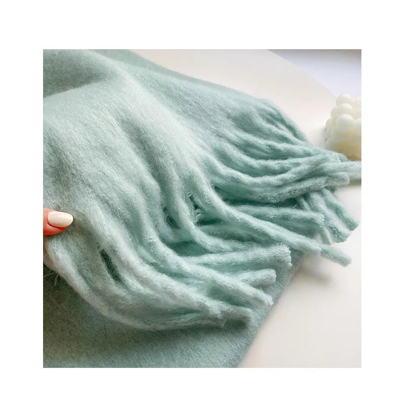 Model feels the soft thickness of the aqua, cashmere scarf