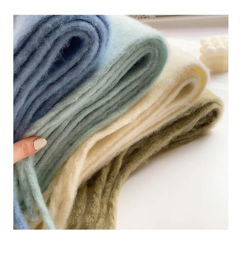 Model feels the soft thickness of the denim blue, aqua, ivory, and olive colored cashmere scarves
