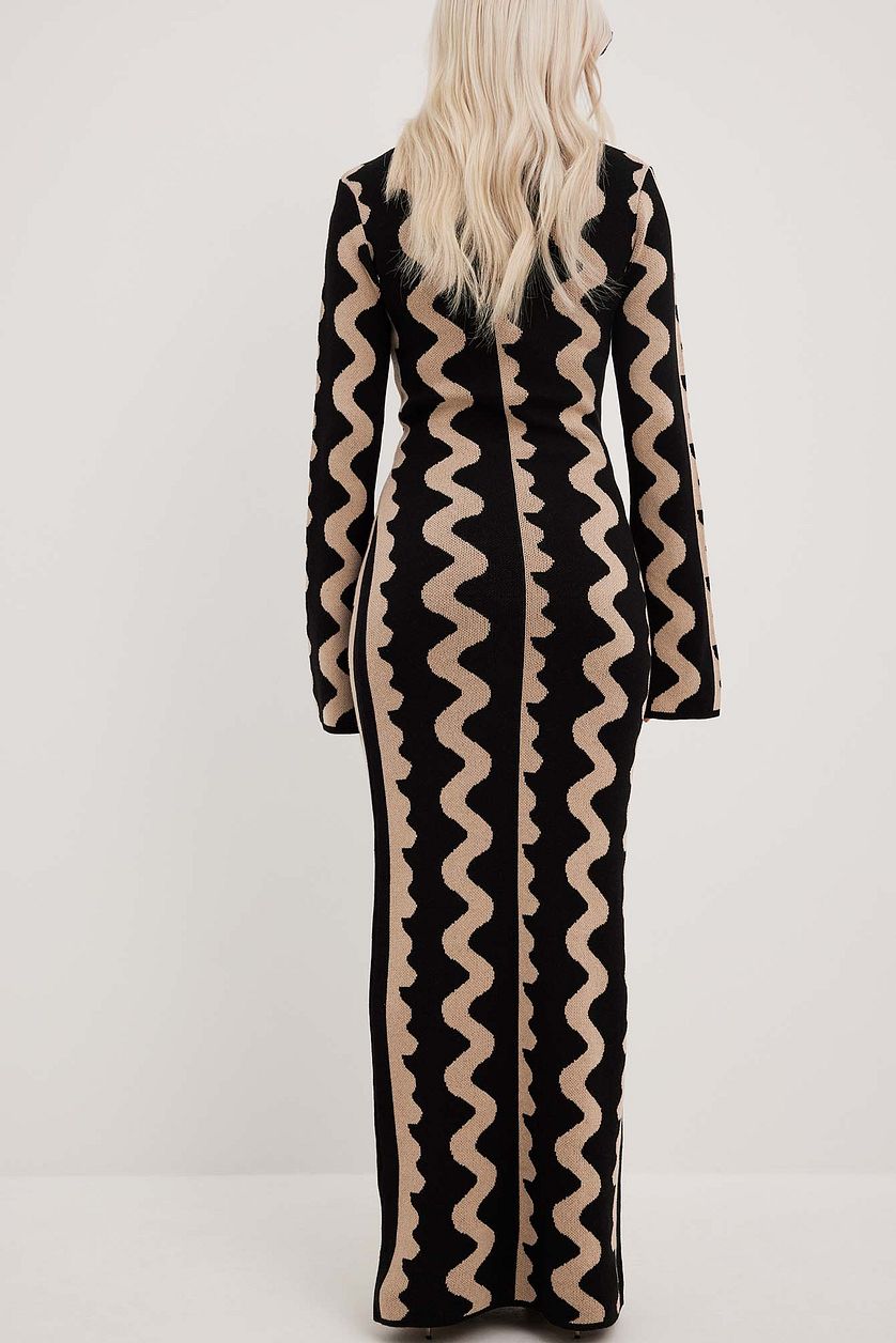 Back view of Gemini Knit Dress by ShoptheKei with a black leather tote bag and oval shaped black sunglasses. Sweater dress maxi length with long flare sleeves. Body conscious. Mod 1960's style dress with vertical wavy squiggle line patterns.