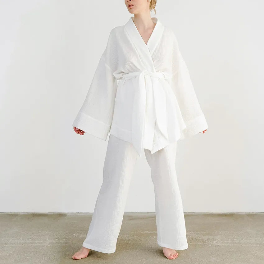 Model wearing white Ira Kimono and Pants set. Breathable cotton lounge set with matching open-front kimono robe, waist sash, and full-length relaxed-fit pants. Cozy fashion perfect for sleep, loungewear, or resort wear.