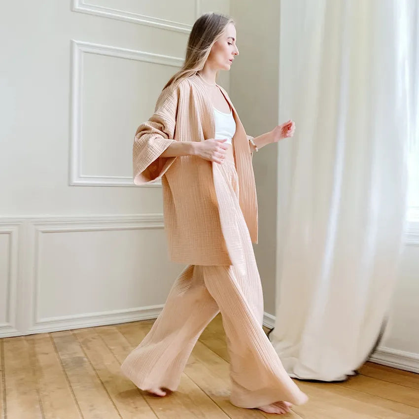 Model wearing almond tan Ira Kimono and Pants set. Breathable cotton lounge set with matching open-front kimono robe, waist sash, and full-length relaxed-fit pants. Cozy fashion perfect for sleep, loungewear, or resort wear.