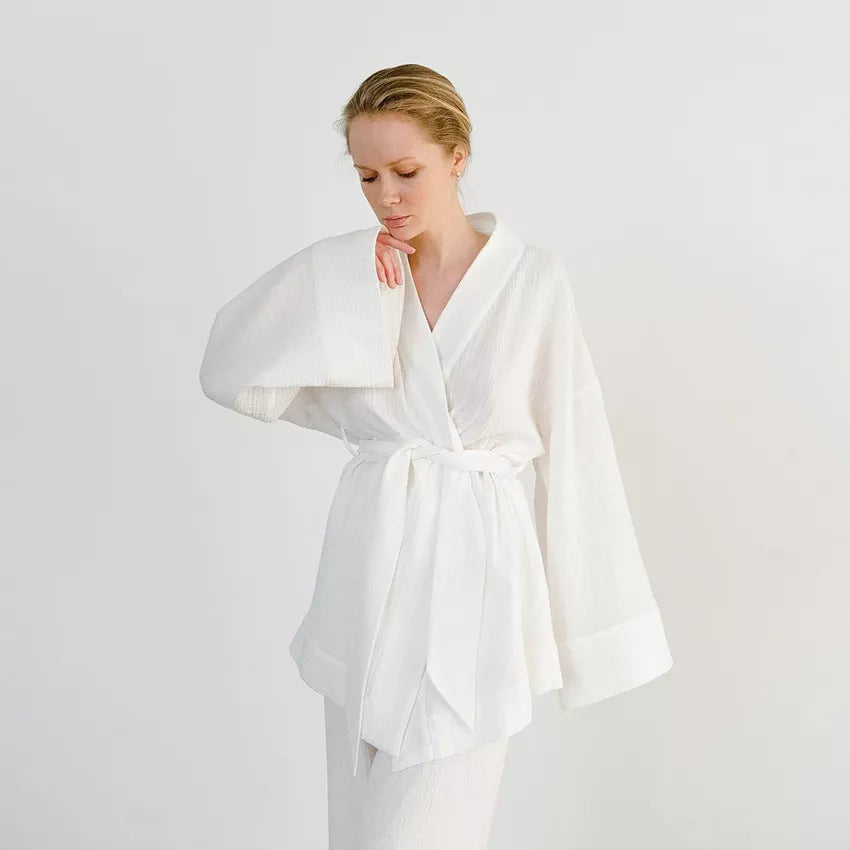 Model wearing white Ira Kimono and Pants set. Breathable cotton lounge set with matching open-front kimono robe, waist sash, and full-length relaxed-fit pants. Cozy fashion perfect for sleep, loungewear, or resort wear.