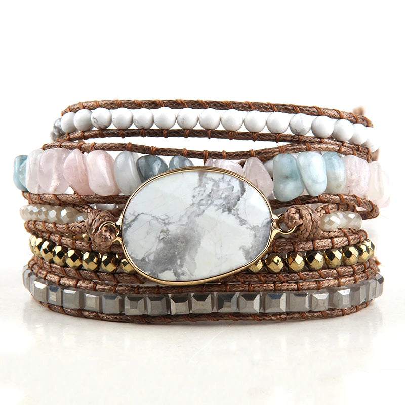 White Bohemian style wrap bracelet with a large center stone and several colorful smaller stones set in a natural cording. The bracelet rests on a white reflective table. White Boho Crystal Bracelet Set - Shop The Kei