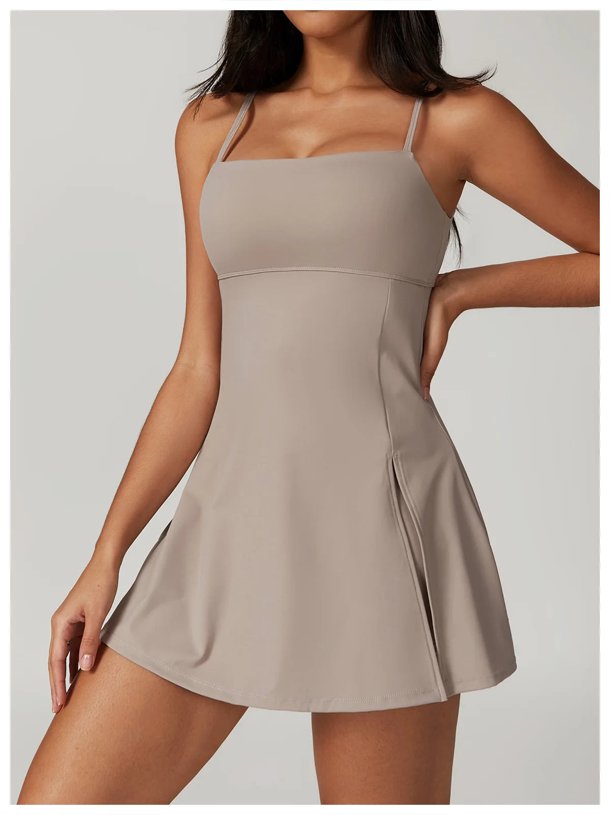 Close up view of the Bree Yoga Dress in dark linen color. Features thin spaghetti straps, straight neckline, fitted bodice, and A-line skirt with a pronounced side slit. Mini-length dress photographed against a neutral background.