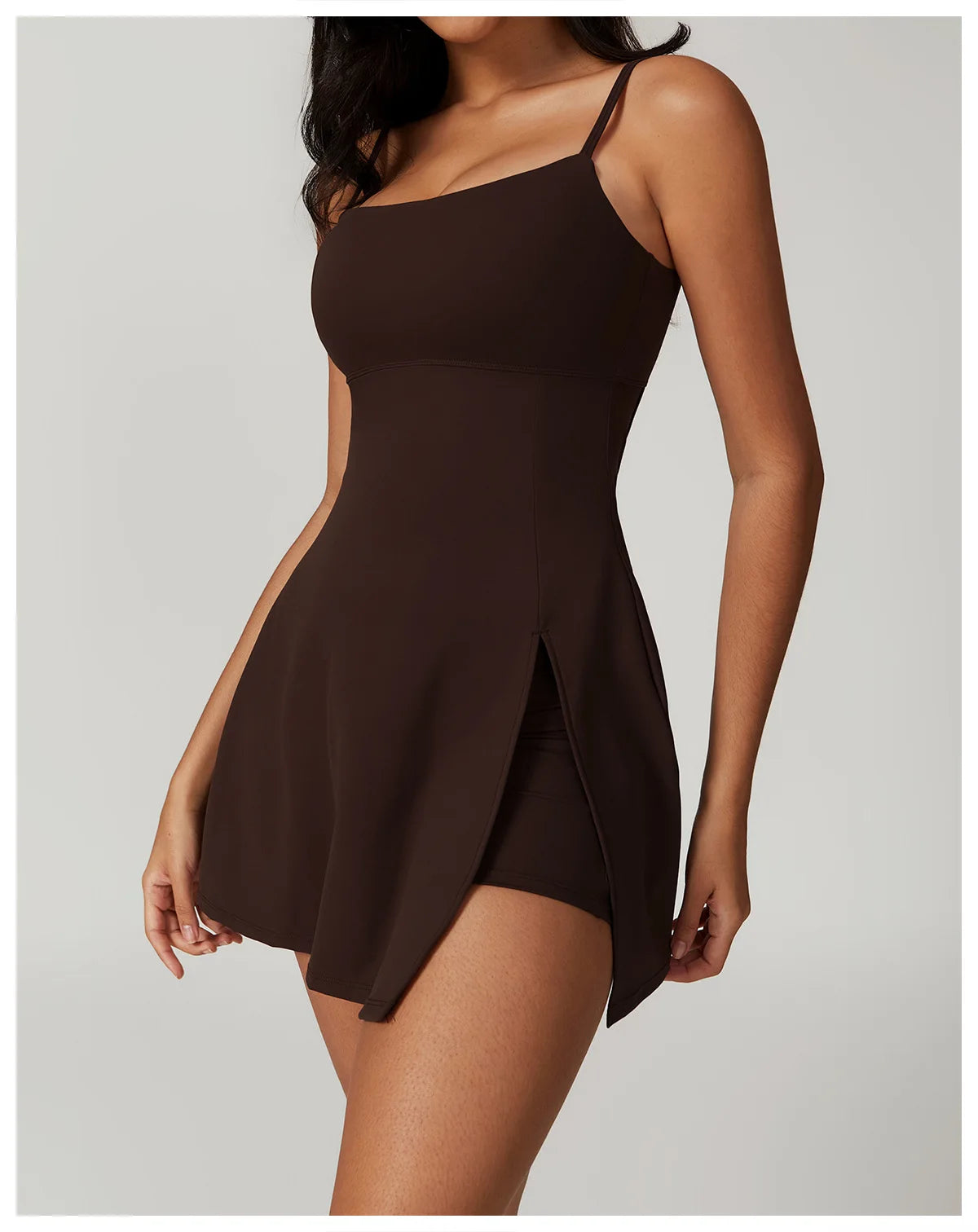Close up view of the Bree Yoga Dress in Espresso brown color. Features thin spaghetti straps, straight neckline, fitted bodice, and A-line skirt with a pronounced side slit. Mini-length dress photographed against a neutral background.