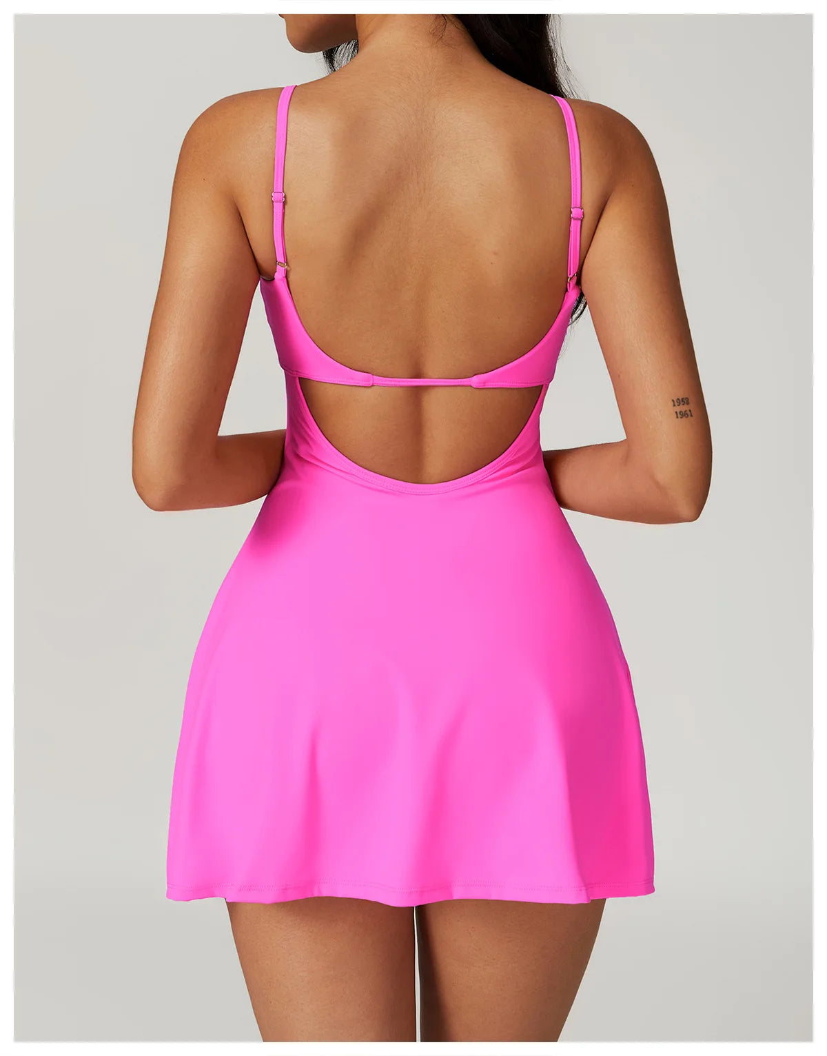 Back view of the Bree Yoga Dress in bright Bubblegum pink color. Shows the open-back design with thin adjustable straps crossing the back, A-line skirt falling to mini length. Photographed against a neutral background.