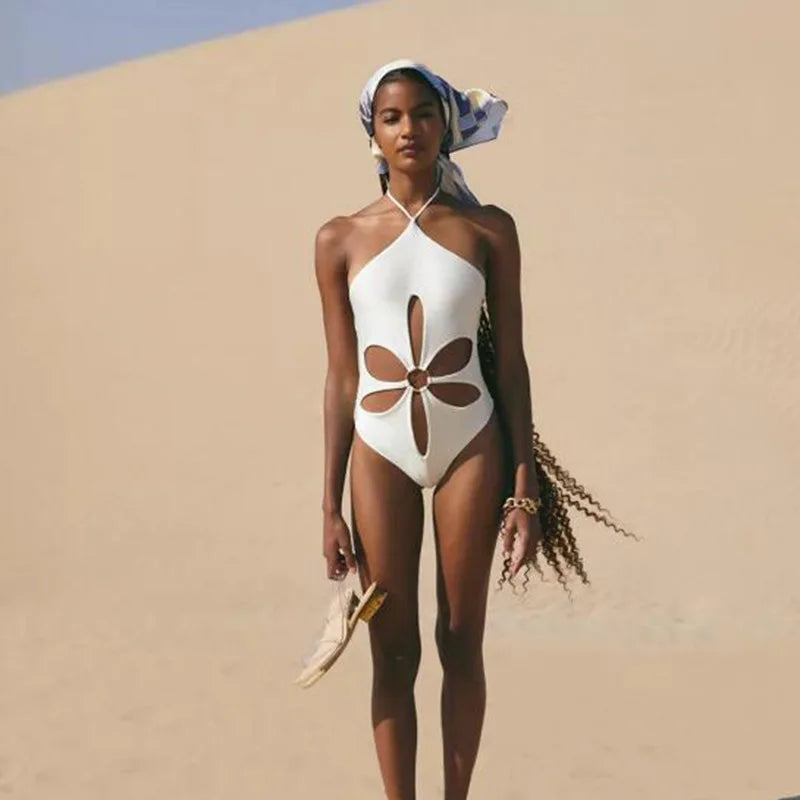 Model wearing Gabby One Piece Swimsuit in white from ShoptheKei.com. Retro-inspired tank top with halter neckline, front flower cut out, and o-ring.