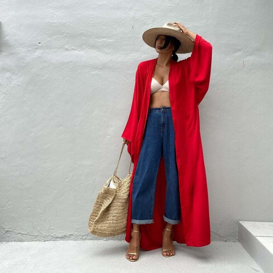 Front view of model wearing the red Sole Kimono from Shop the Kei with a white bikini top, baggy jeans, gold heels, straw hat and beach tote . A Bohemian-style ankle-length beach cover-up kimono with wide sleeves and matching waist sash, perfect for vacation, poolside, or post-swim lounging.
