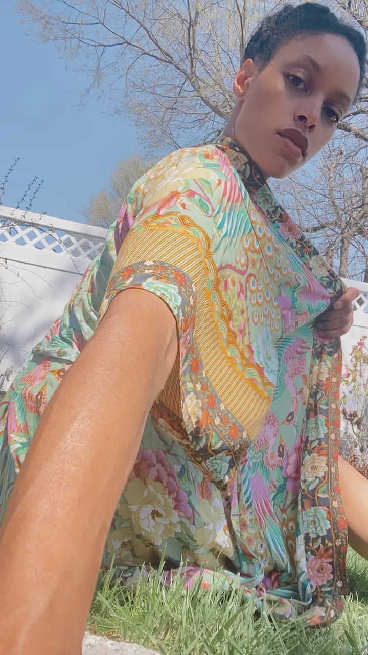 Video of model wearing Nyma Kimono from Shop The Kei swim coverup collection. Bohemian-style Nyma Kimono with open front, waist sash, wing sleeves, and ankle-length floral print rayon fabric. Elegant and flowy coverup style