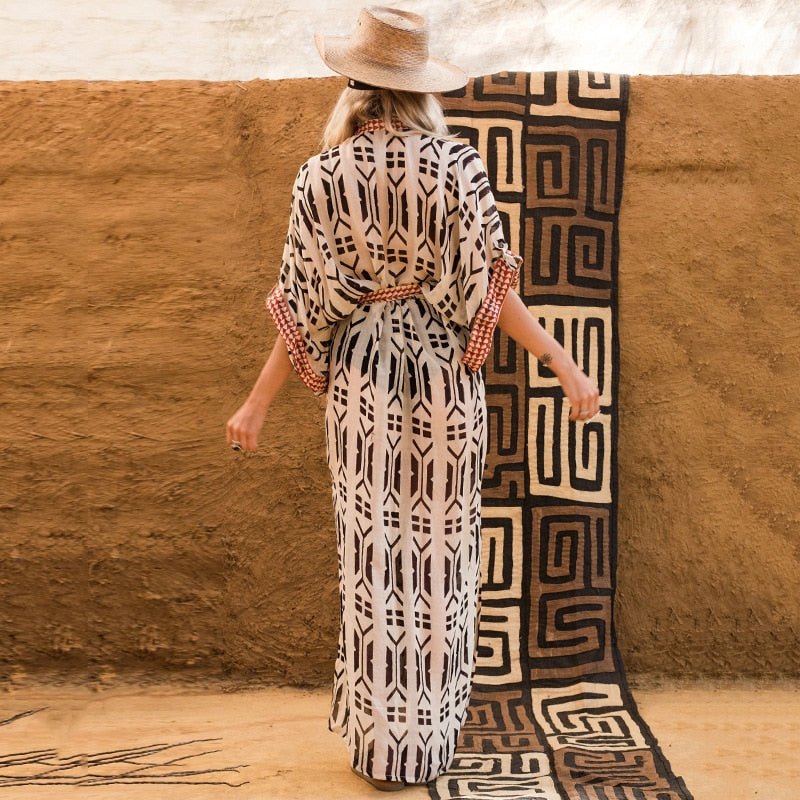 Back view of blonde model wearing Ethola Kimono from Shop The Kei Swim collection. Bohemian ankle-length beach cover-up kimono with an earthy geometric print and waist tie. Lightweight, flowy, and perfect for vacations.