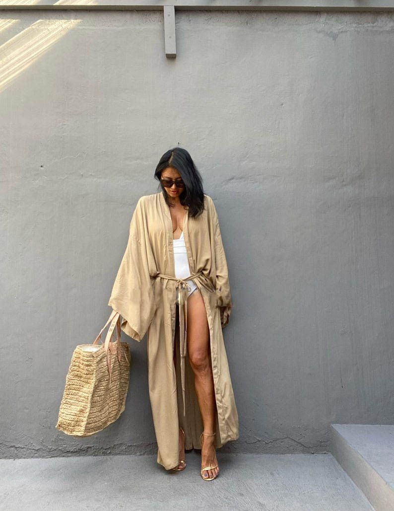 Front view of model wearing the Sand Sole Kimono from Shop the Kei with a white one piece swimsuit, straw tote, and gold heels. A Bohemian-style ankle-length beach cover-up kimono with wide sleeves and matching waist sash, perfect for vacation, poolside, or post-swim lounging.