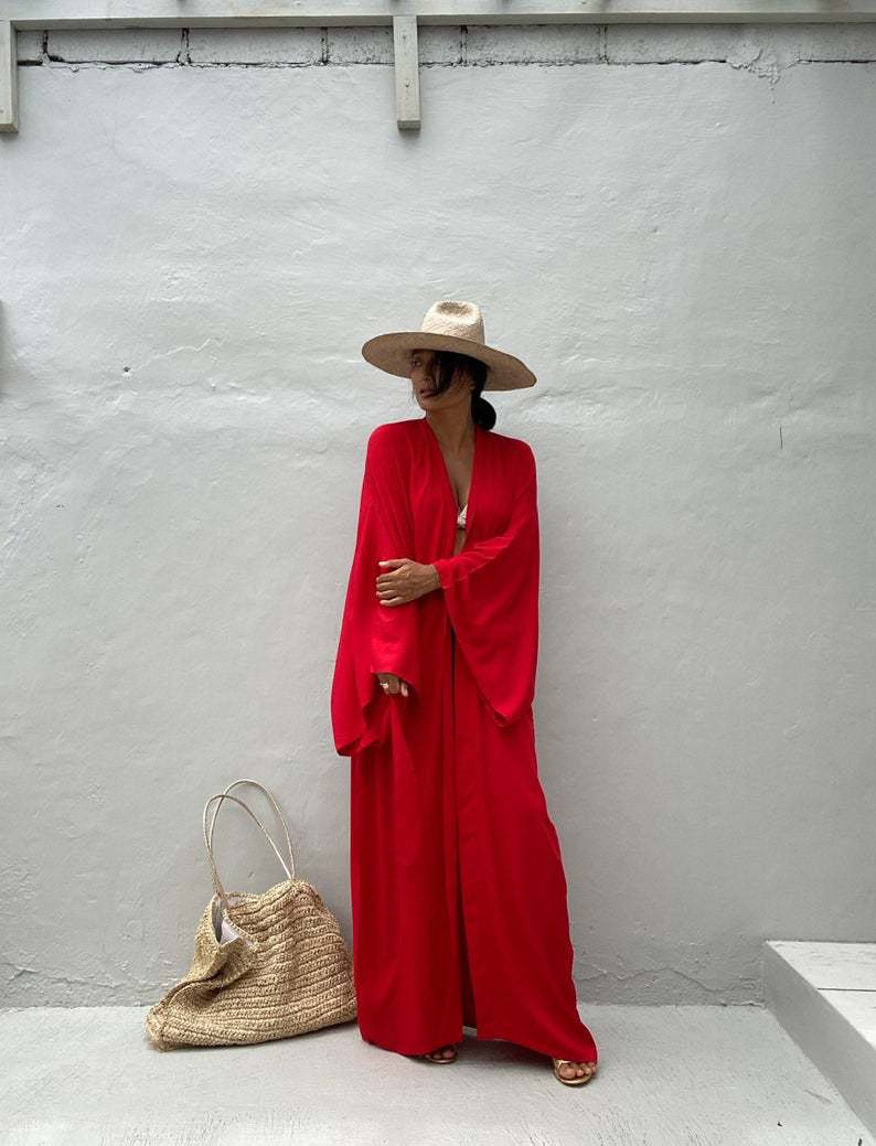 Front view of model wearing the red Sole Kimono from Shop the Kei shown with a white bikini top, gold heels, straw hat and beach tote . A Bohemian-style ankle-length beach cover-up kimono with wide sleeves and matching waist sash, perfect for vacation, poolside, or post-swim lounging.