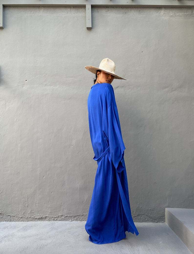Side view of model wearing the royal blue Sole Kimono from Shop the Kei. A Bohemian-style ankle-length beach cover-up kimono with wide sleeves and matching waist sash, perfect for vacation, poolside, or post-swim lounging.