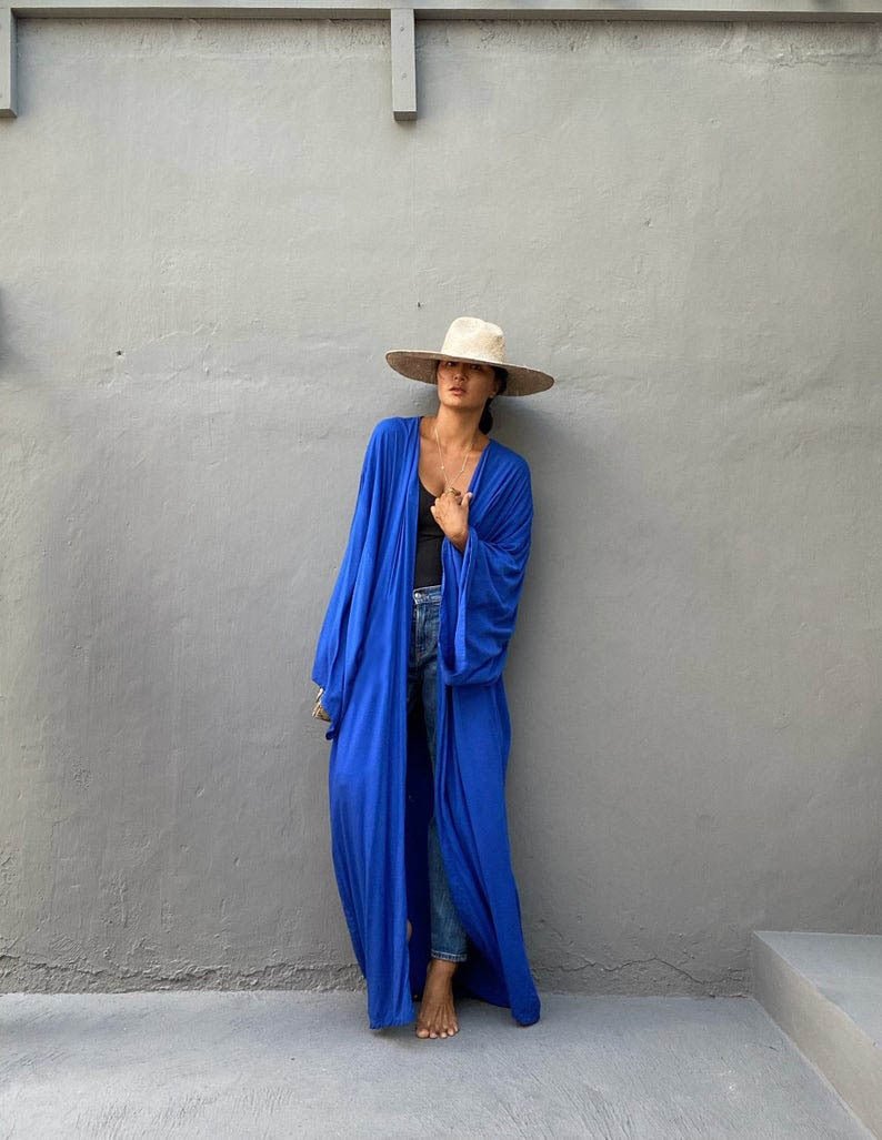 Model is wearing the royal blue Sole Kimono from Shop the Kei with jeans. A Bohemian-style ankle-length beach cover-up kimono with wide sleeves and matching waist sash, perfect for vacation, poolside, or post-swim lounging.