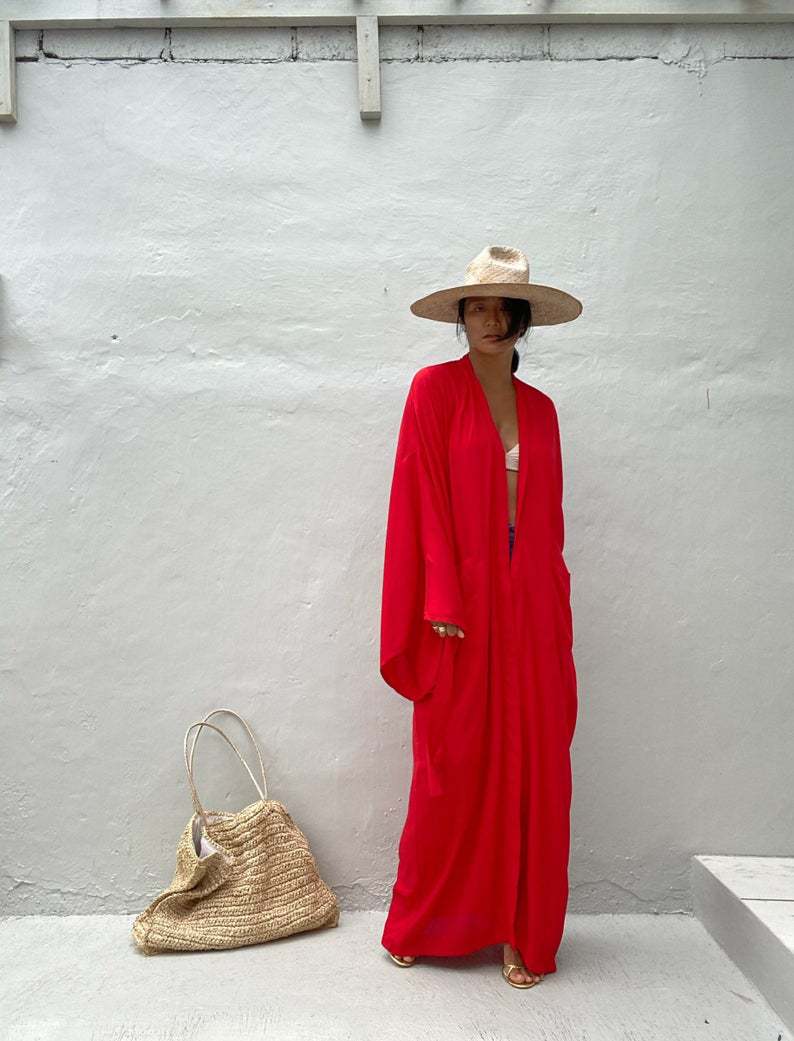 Front view of model wearing the red Sole Kimono from Shop the Kei shown with a white bikini top, gold heels, straw hat and beach tote . A Bohemian-style ankle-length beach cover-up kimono with wide sleeves and matching waist sash, perfect for vacation, poolside, or post-swim lounging.