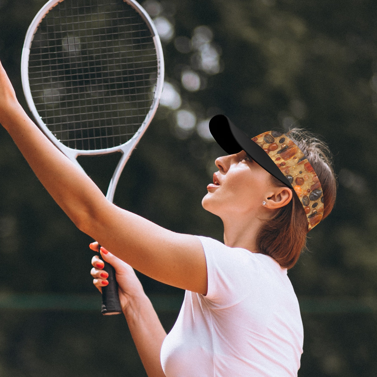 A woman on a tennis court wearing a black visor with a colorful pizza-pattern brim, a white t-shirt, and holding a tennis racket.
