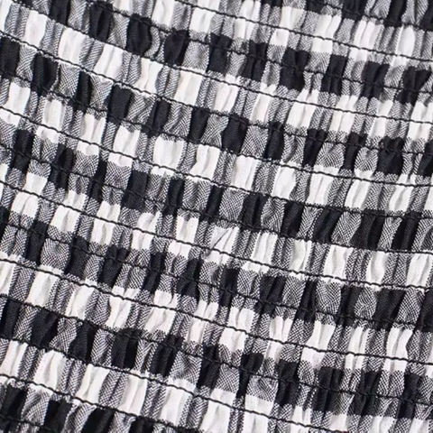 Close-up detail of the Pixi Dress showing black and white gingham fabric with shirred bodice