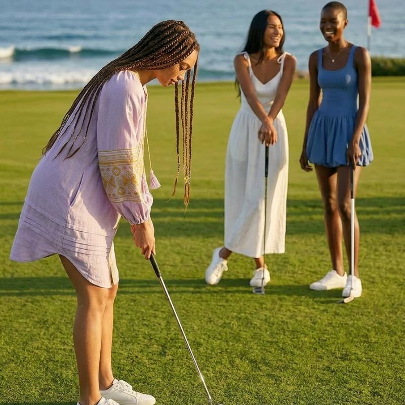 Woman playing golf on a grassy field with two other women in the background.