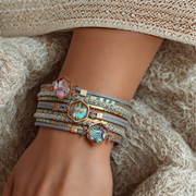 Close-up of a wrist wearing multiple decorative bracelets on a textured fabric background