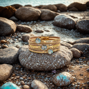 Gold bracelets with gemstones on a stone by the sea