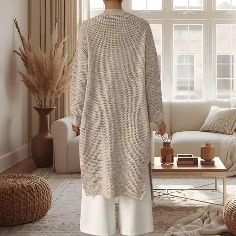 Person wearing a long beige cardigan in a cozy living room.