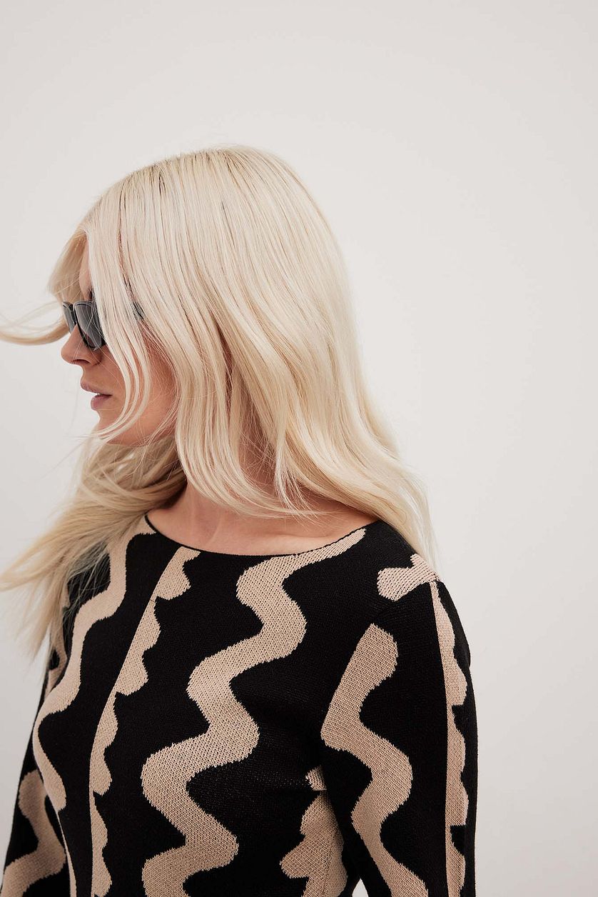 Close up of Gemini Knit Dress by ShoptheKei. Sweater dress maxi length with long flare sleeves. Body conscious. Mod 1960's style dress with vertical wavy squiggle line patterns.