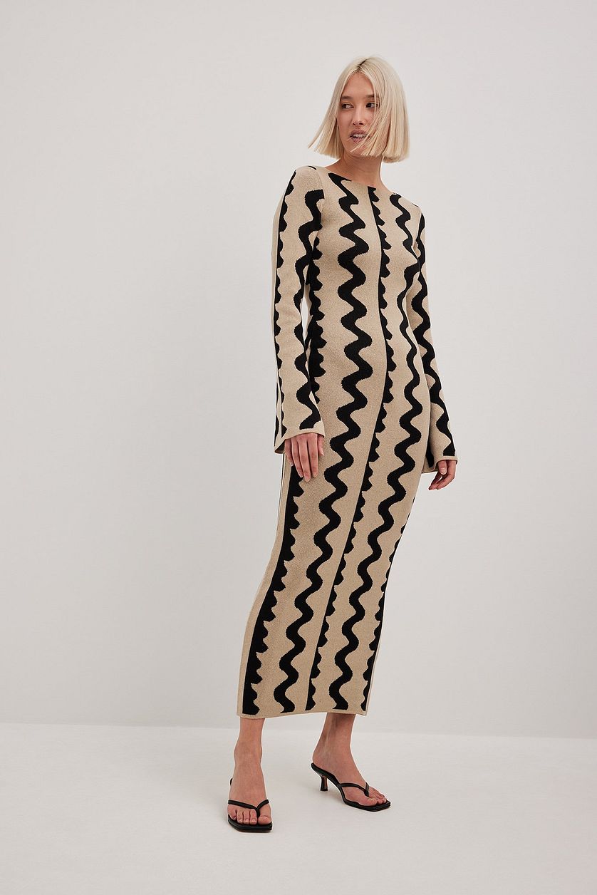 Model wears Gemini Knit Dress by ShoptheKei with a black kitten heels. Sweater dress maxi length with long flare sleeves. Body conscious. Mod 1960's style dress with vertical wavy squiggle line patterns.