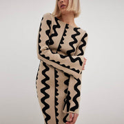 Model embraces the soft Gemini Knit Sweater Dress by ShoptheKei. Sweater dress maxi length with long flare sleeves. Body conscious. Mod 1960's style dress with vertical wavy squiggle line patterns.