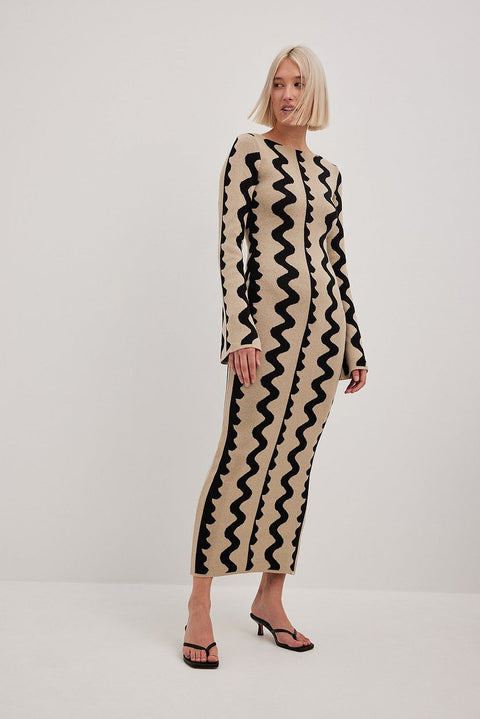Model wears Gemini Knit Dress by ShoptheKei with a black kitten heels. Sweater dress maxi length with long flare sleeves. Body conscious. Mod 1960's style dress with vertical wavy squiggle line patterns.