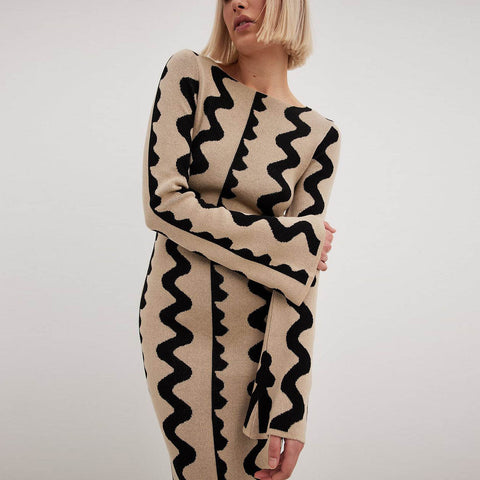 Model embraces the soft Gemini Knit Sweater Dress by ShoptheKei. Sweater dress maxi length with long flare sleeves. Body conscious. Mod 1960's style dress with vertical wavy squiggle line patterns.