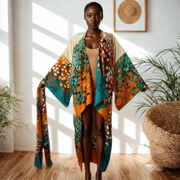 Colorful patterned kimono on a dark skinned woman against a white wall with natural furniture in a cozy living space with plants and wood floors
