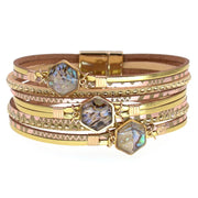 Stack of gold and rose gold bracelets with gemstone accents on a white background
