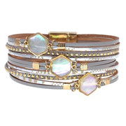 Stack of gold and silver bracelets with hexagonal gemstones on a white background