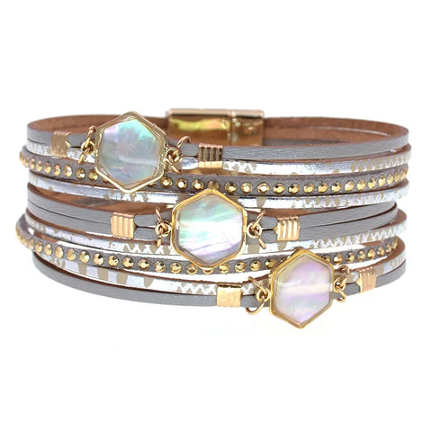 Stack of gold and silver bracelets with hexagonal gemstones on a white background