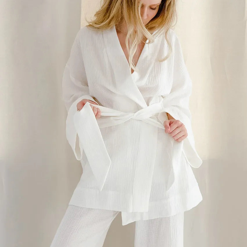 Model wearing white Ira Kimono and Pants set. Breathable cotton lounge set with matching open-front kimono robe, waist sash, and full-length relaxed-fit pants. Cozy fashion perfect for sleep, loungewear, or resort wear.