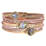 Stack of pink and gold bracelets with gemstone accents on a white background