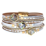 Stack of multi-layered bracelets with gemstone accents on a white background
