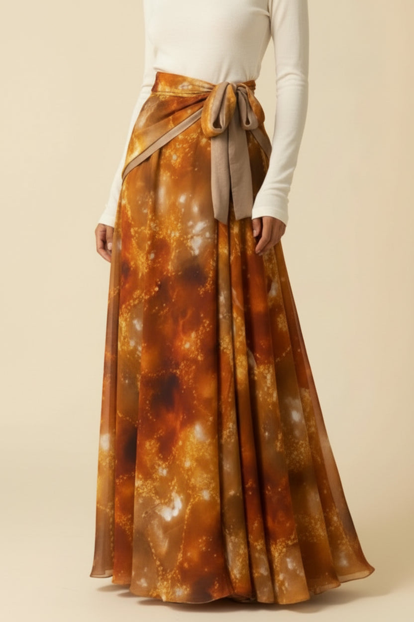 Woman wearing a long, patterned skirt and long sleeve cream top against a beige background