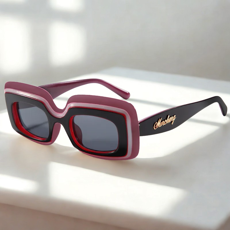 Orchid Retro Shades sunglasses resting on a sunlit white surface, the mauve-pink frame with a red inner rim catching dramatic window-light shadows.