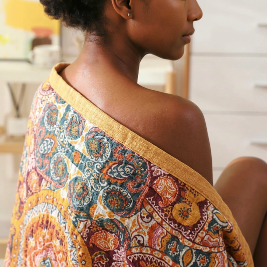 Woman wrapped in the Runa Cotton Blanket in a red and orange paisley medallion print, seen from behind
