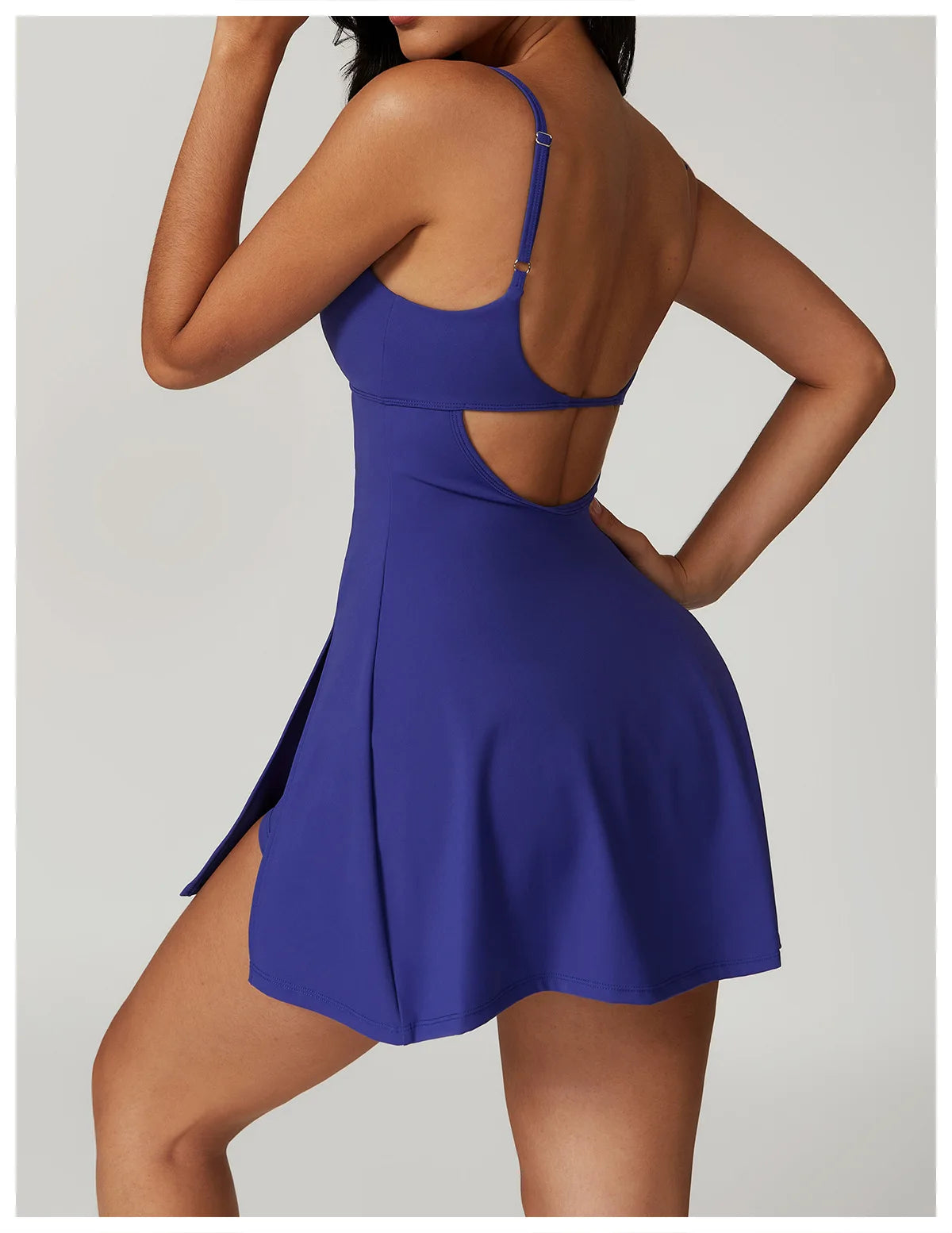 Side - back view of the Bree Yoga Dress in royal blue color. Shows the open-back design with thin adjustable straps crossing the back, A-line skirt falling to mini length. Photographed against a neutral background.