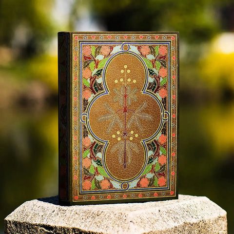 Decorative book with intricate designs on a stone surface with a blurred natural background
