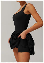 Side view of a model wearing the black Rinay Sport Dress from ShoptheKei activewear collection. Image reveals a pair of shorts sewn inside the dress and flat side pocket large enough for a phone or gym card.