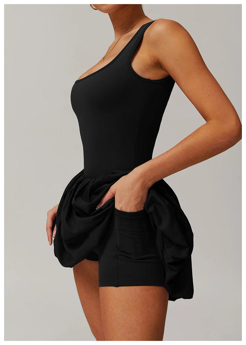 Side view of a model wearing the black Rinay Sport Dress from ShoptheKei activewear collection. Image reveals a pair of shorts sewn inside the dress and flat side pocket large enough for a phone or gym card.