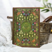 Decorative notebook with floral patterns on a white surface with plants in the background