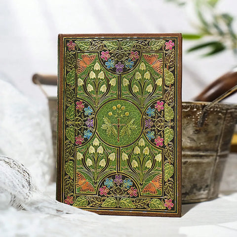 Decorative notebook with floral patterns on a white surface with plants in the background