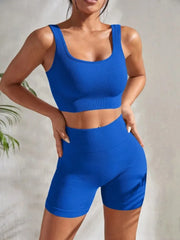 Model wearing Zen Yoga Shorts Set in bright blue. Soft textured rib knit tank top with matching slim fit high waist shorts provide support and comfort during your movements. Model stands with hands on her hips in front of a white background.